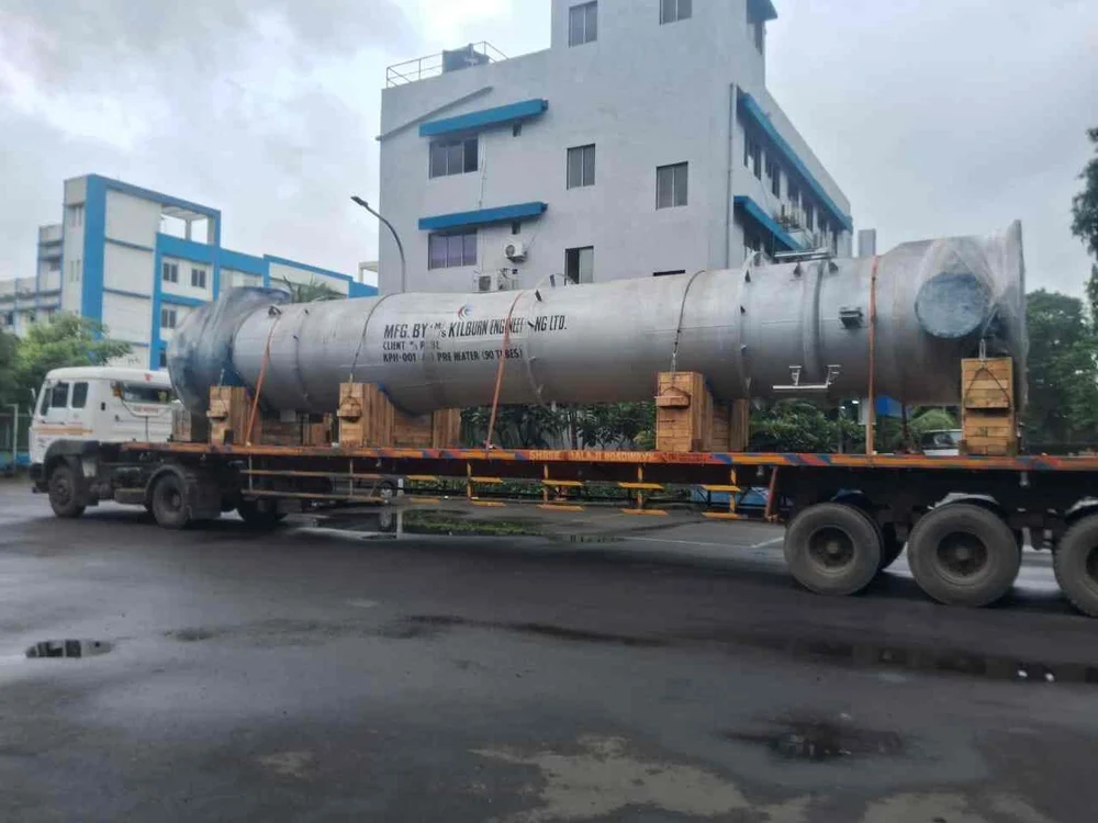 Long cylindrical industrial vessel secured on a road trailer
